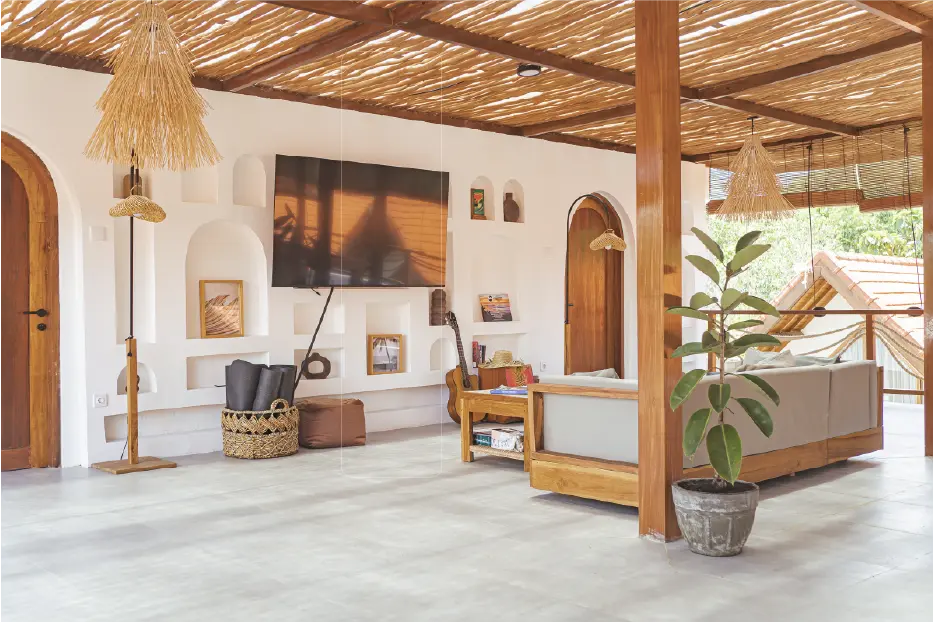 Bright, tropical-style living room with white arched wall niches, a wooden sofa, and a bamboo ceiling