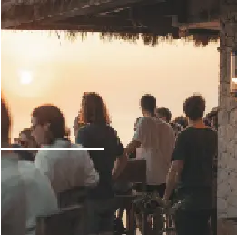 People socializing at an outdoor bar during a hazy sunset