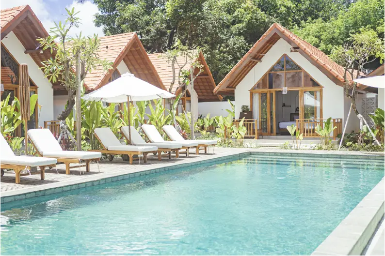 White A-frame bungalows with orange roofs overlooking a swimming pool with lounge chairs