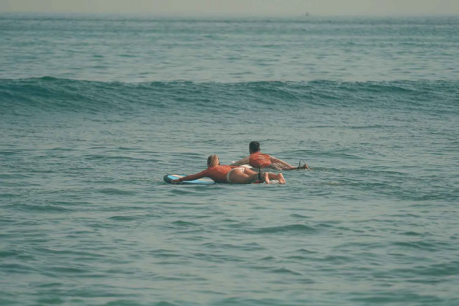 Surf Camp Student and Surf Guide paddling together into the lineup.