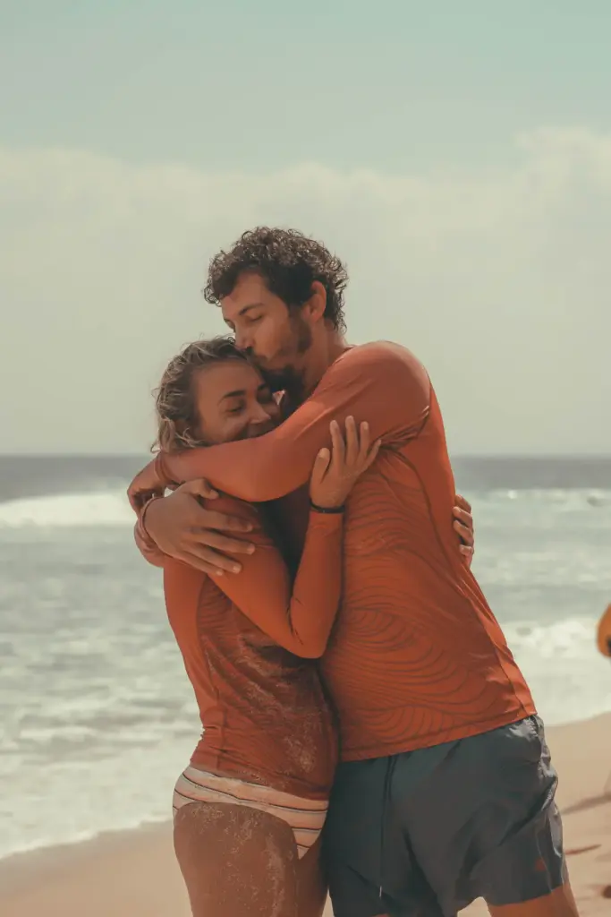 A couple embracing on the beach at CARI Surf Camp